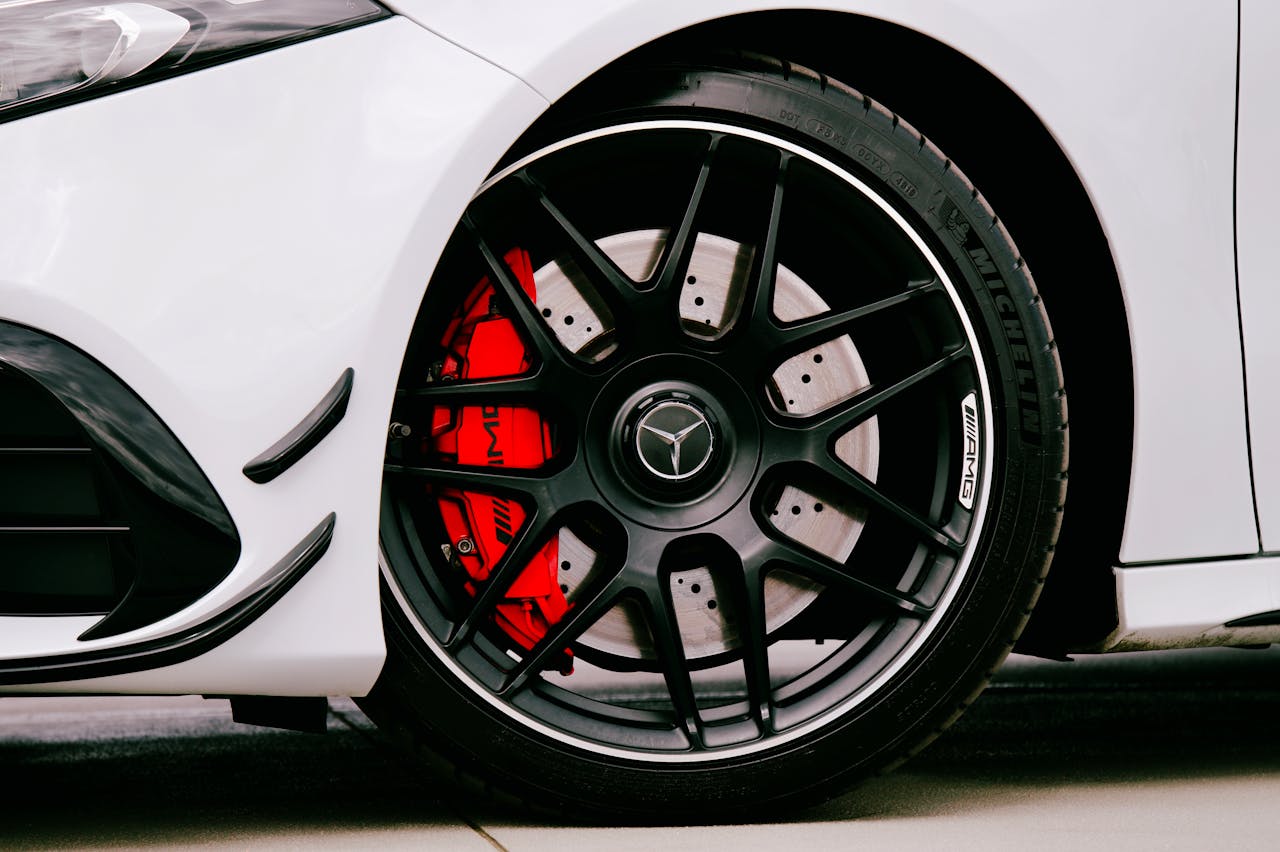 Detailed view of a Mercedes Benz car wheel featuring a striking red brake caliper and stylish black alloy rim.