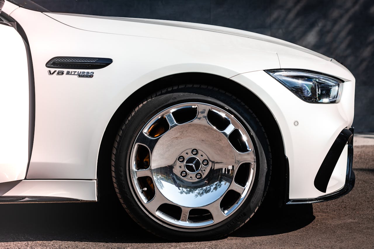 Detailed view of a luxury car showcasing a chrome wheel and elegant design, reflecting high performance.